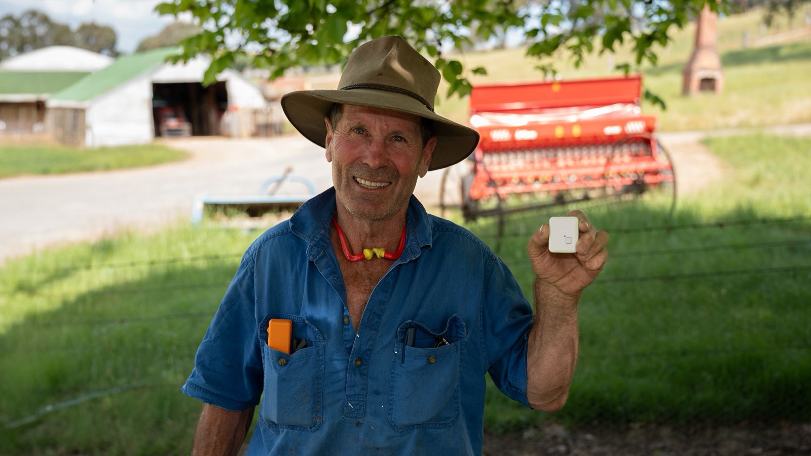 An Australian farmer holding the AirAgri personal location device on his property.
